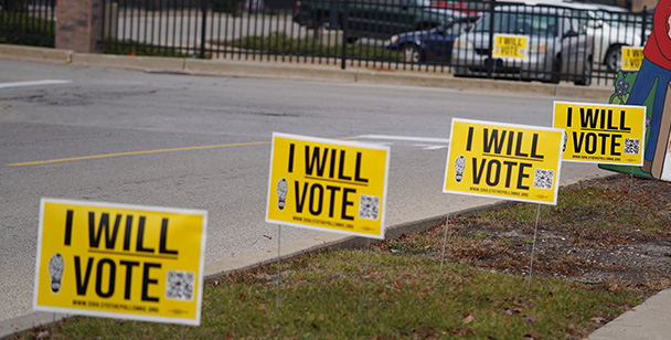 A row of I Will Vote signs line the street.