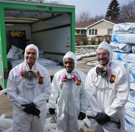 Three men dressed in hazmat suits work to remove led from Milwaukee homes.